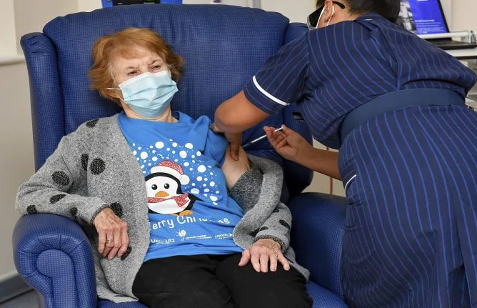 Nurse May Parsons prepares 90-year-old Margaret Keenan, the first patient in the UK to receive the Pfizer-BioNTech COVID-19 vaccine, at University Hospital, Coventry, England on December 8, 2020