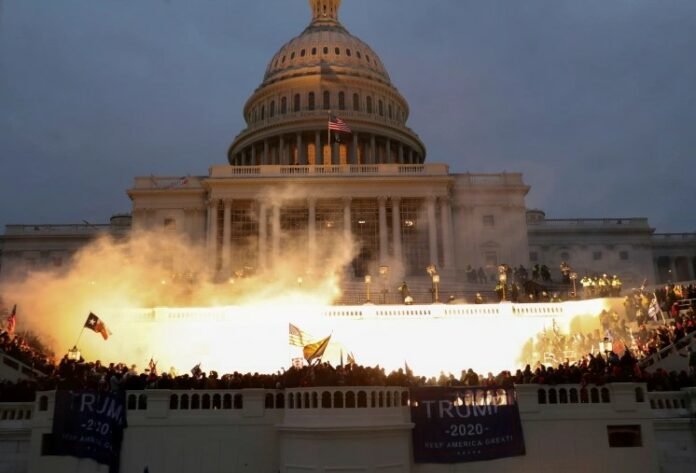 An explosion caused by a police munition is seen while supporters of US President Trump gather in front of the US Capitol building