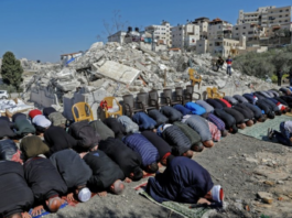 Palestinian Muslim worshippers attend Friday noon prayers in front of the rubble of buildings demolished by Jerusalem municipality workers, reportedly built without an Israeli construction permit, in the mostly-Arab East Jerusalem neighbourhood of Issawiya