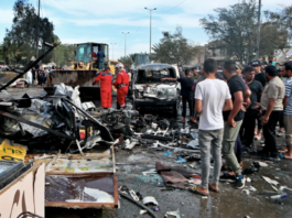 People and security forces inspect the scene of an explosion at a crowded outdoor used furniture market in Sadr City area, Baghdad Iraq, Thursday, April 15, 2021