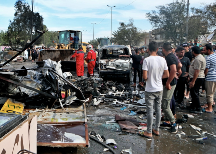 People and security forces inspect the scene of an explosion at a crowded outdoor used furniture market in Sadr City area, Baghdad Iraq, Thursday, April 15, 2021