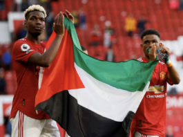Manchester United's Paul Pogba (L) and Amad Diallo applaud fans while holding a Palestinian flag