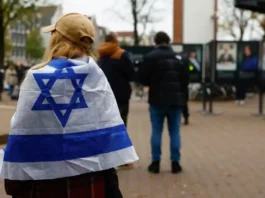 A woman wrapped in an Israel flag stands outside the place where mayor of Amsterdam Femke Halsema attends a press conference following the violence targeting fans of an Israeli soccer team, in Amsterdam, Netherlands, November 8, 2024. (photo credit: PIROSCHKA VAN DE WOUW/REUTERS)