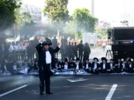 Police officers in Bnei Brak, Israel use water cannons as haredi Orthodox Jewish men block a main highway to protest efforts to allow the state to draft Haredi yeshiva students into military service, June 2, 2024
