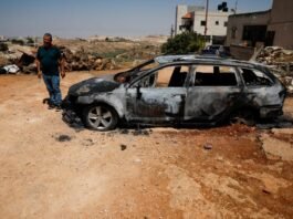 A Palestinian inspects a burnt car after a settler attack in Kafr Malik, June 26, 2025