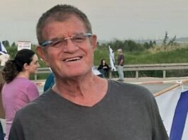 A Red Cross worker inspects communication equipment as armed Hamas personnel oversee the transfer of a hostage’s body in Gaza