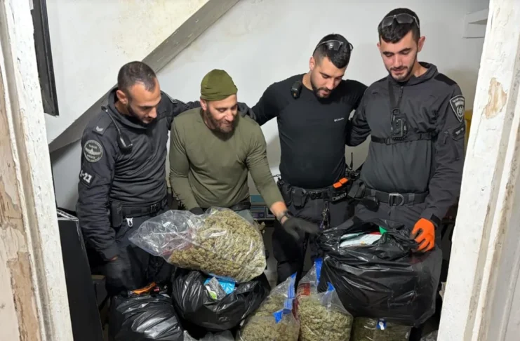 Israeli police officers inspect packages of suspected cannabis seized during a raid on a Tel Aviv apartment in Kfar Shalem